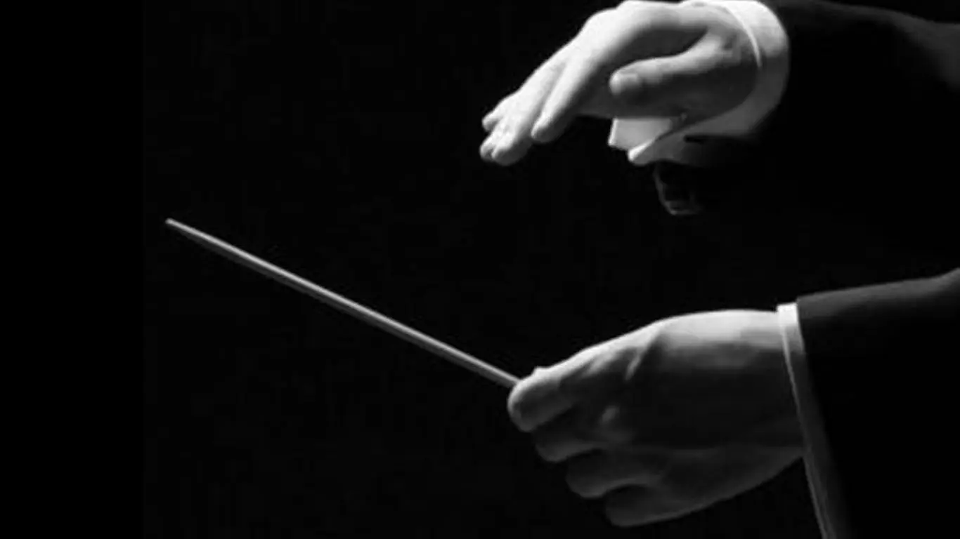 Mãos de um maestro conduzindo com a batuta